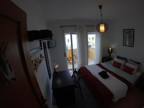a bedroom with a bed and a television and a balcony at Peniche Surf Lodge 2 in Peniche