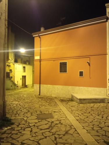 a building with an orange wall and a stone street at L'altra casa 1933 in Rionero in Vulture