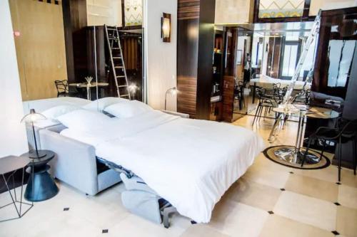 - une chambre avec un grand lit blanc, des tables et des chaises dans l'établissement Studio boisé à 2 pas du jardin du Luxembourg, à Paris