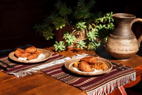two plates of food on a wooden table at Хата Різьбяра - Закуток in Beloberëzka