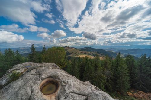 a rock with a hole in it on a mountain at Хата Різьбяра - Закуток in Beloberëzka