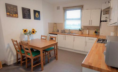 a kitchen with a wooden table and chairs and a kitchen with white cabinets at Very spacious two bedroom converted apartment in East Croydon in Croydon