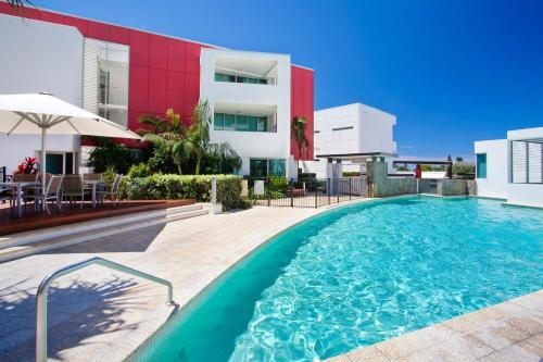 a swimming pool in front of a building at Element on Coolum Beach in Coolum Beach