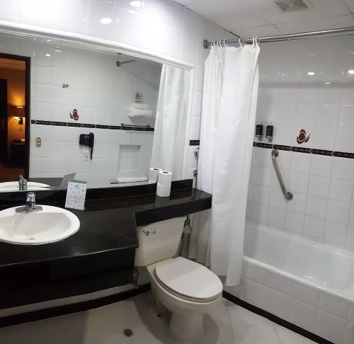 a bathroom with a toilet and a sink and a tub at Hotel El Conquistador in Cuenca