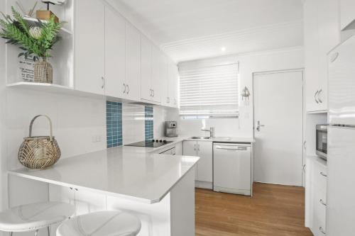 a white kitchen with white cabinets and white appliances at Beachcomber Unit 2 7 Dingle Ave in Caloundra