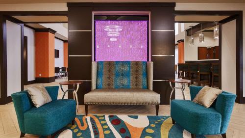 a lobby with two blue chairs and a purple screen at Best Western Premier Ashton Suites - Willowbrook in Houston