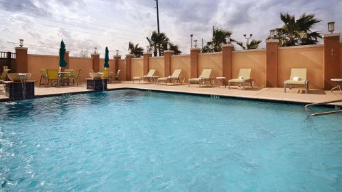 a large swimming pool with chairs and tables at Best Western Premier Ashton Suites - Willowbrook in Houston