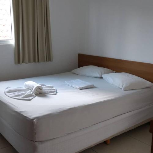 a bed with white sheets and two towels on it at Mariba's Pousada in João Pessoa