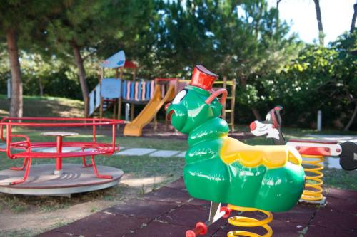 a playground with a green dinosaur and a swing at Pizzomunno Vieste Palace Hotel in Vieste