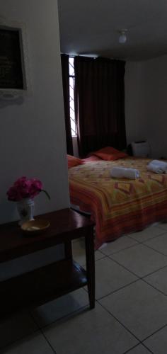 a bedroom with a bed and a table with flowers on it at La Casa del Che Fernando in Lima