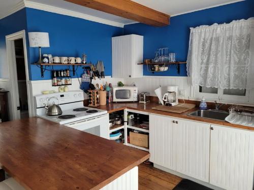 una cucina con armadi bianchi e parete blu di Les Chatons Azur - Chalet a Saint-Fabien