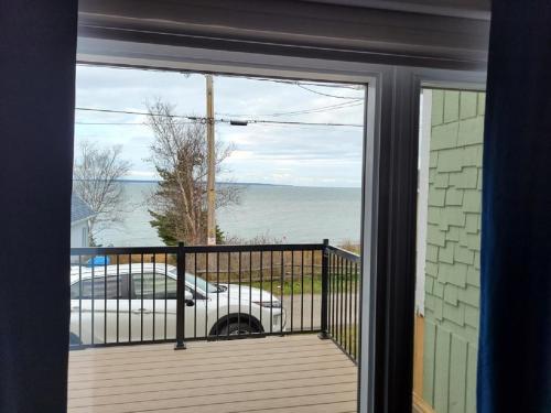 a door to a balcony with a view of the ocean at Les Chatons Azur - Chalet in Saint-Fabien