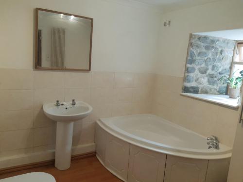 a bathroom with a bath tub and a sink at Plough Cottage is a 18th Century barn conversion offering a tranquil rural retreat 9 miles from the Lake District National Park in Carnforth