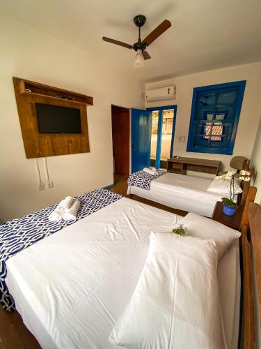 a bedroom with two beds and a flat screen tv at Pousada Doce Villa in Capitólio