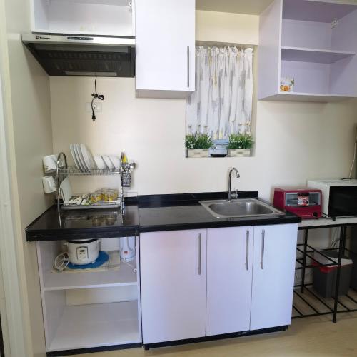a kitchen with white cabinets and a sink at Avida Davao by davaobnb & Lemonique Homes in Davao City