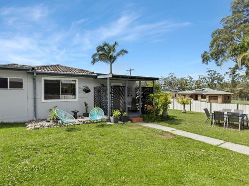 a house with a yard with a table and chairs at Bikini Bottoms by Experience Jervis Bay in Huskisson