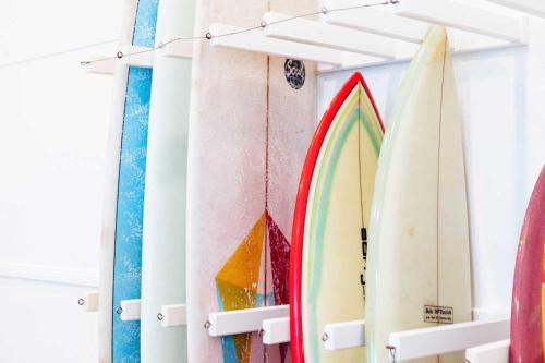 Un tas de planches de surf sont alignées contre un mur dans l'établissement The Surf House, à Byron Bay