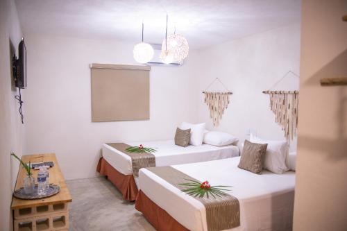 Dos camas en una habitación con paredes blancas. en Ahava Hotel, en Playa del Carmen