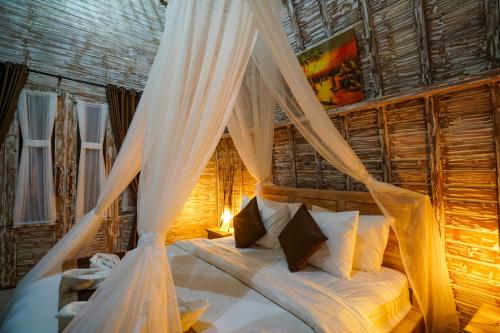 a bedroom with a canopy bed with white drapes at Unicorn Bungalow in Nusa Penida