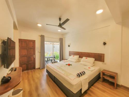 a bedroom with a large bed with a ceiling fan at Dhonkamana Stay in Thoddoo