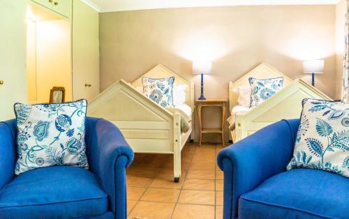 a room with two blue chairs and two beds at Halliwell Country Inn in Howick