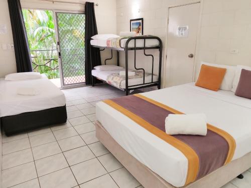 a bedroom with two beds and a balcony at Coconut Grove Holiday Apartments in Darwin