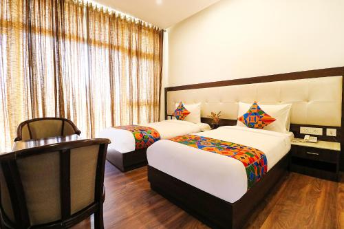 a hotel room with two beds and a chair at FabHotel Oyster Villa in Gurgaon