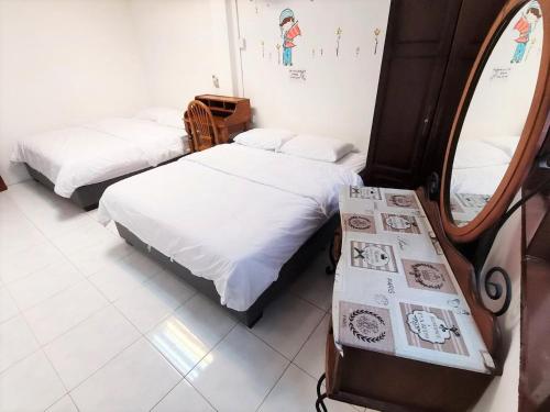 two beds in a room with a mirror at Singtown Guesthouse in Mersing