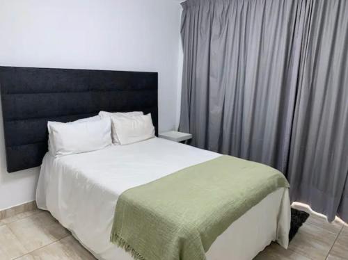 a bedroom with a large white bed with a black headboard at Lillys Quarter 1 - Newly Renovated! in Sandton