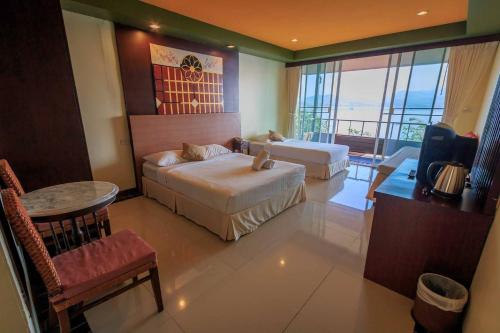 a hotel room with two beds and a television at Raya Buri Resort Kanchanaburi in Si Sawat