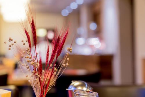 a vase filled with red flowers sitting on a table at Hotel Bacchus in Bensheim
