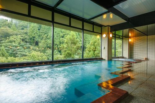 a large swimming pool with a view of the mountains at Yamanaka Onsen Hanatsubaki in Kaga