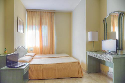 a bedroom with a bed and a desk with a laptop at Hotel AMALFI in Lido di Jesolo