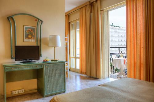 a bedroom with a bed with a tv and a mirror at Hotel AMALFI in Lido di Jesolo