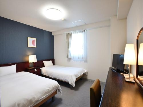 um quarto de hotel com duas camas e uma televisão em Chisun Hotel Koriyama em Koriyama