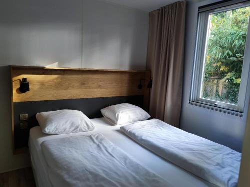 two twin beds in a bedroom with a window at Motel- Bungalow-& Chaletpark de Brenkberg in Schinveld