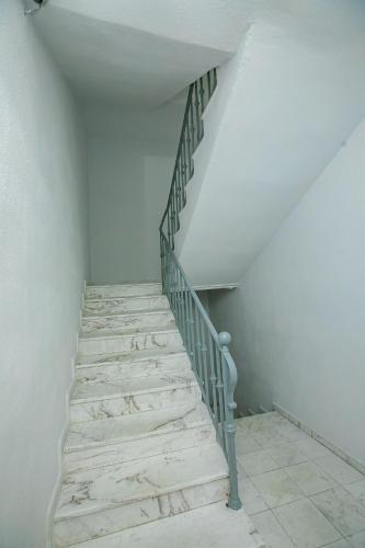 a staircase in a room with white walls and white floors at Aparthouse Heaven in Sandanski