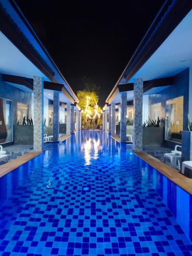 a swimming pool at night with blue tiles on the floor at Yuwadee Resort in Chalong