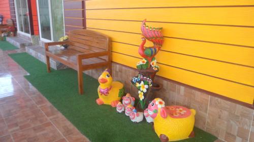 a room with a yellow wall with a bench and toys at บุญจินดา รีสอร์ท in Ban Phayom