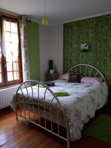 a bedroom with a bed with a green wall at Le Pingouin in Bennecourt