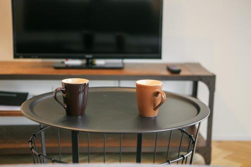 two coffee mugs sitting on a table in front of a television at trive osu west 最大9名宿泊可能 1台無料駐車場付き in Minami-sotoborichō