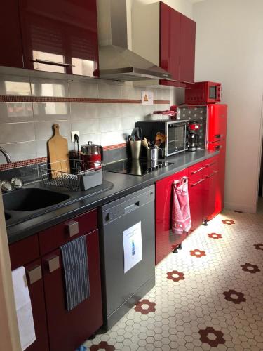 La cuisine est équipée de placards rouges et d'un four avec plaques de cuisson. dans l'établissement Le Rameau, à Sainte-Menehould