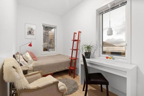 特羅姆瑟的住宿－SKIR 2 Bdr CORNER VIEW APARTEMENT，客厅配有床、书桌和窗户
