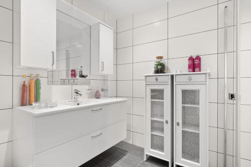 uma casa de banho branca com armários brancos e um lavatório em SKIR 2 Bdr CORNER VIEW APARTEMENT em Tromsø