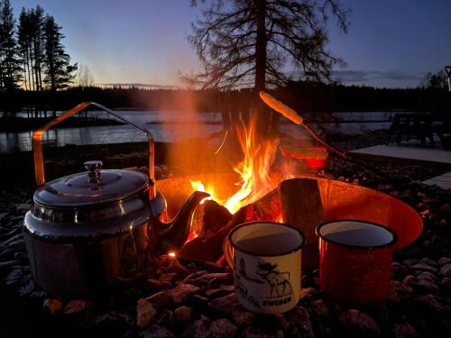 a campfire with a pot and two pots and pans at Projekt Schwedenalm in Furudal