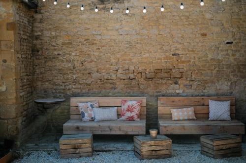 un banco de madera sentado contra una pared de ladrillo con almohadas en Le Domaine de l'Hostellerie en Le Fresne-Camilly