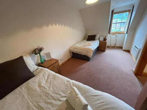 a small bedroom with two beds and a window at Lovely and Spacious 2BD Holiday Retreat Ballater in Ballater