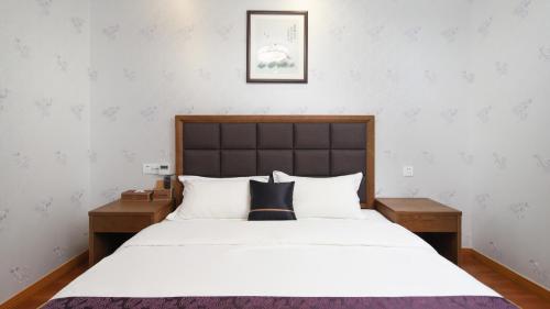 una camera da letto con un grande letto bianco con due tavoli di Floral Hotel Wuxi Shengziling a Wuxi