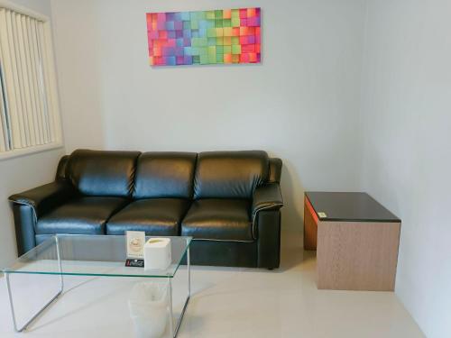 a black leather couch in a living room with a table at Praso Residence in Bangkok