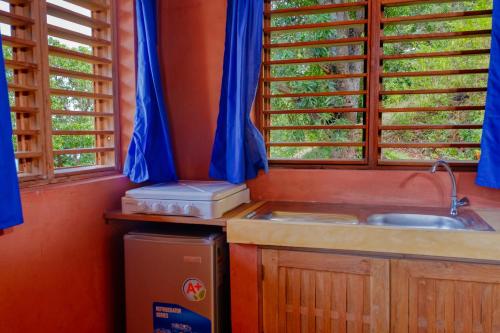 eine Küche mit einer Spüle und einer Theke mit Fenstern in der Unterkunft Colibri Lodge in Ambatoloaka